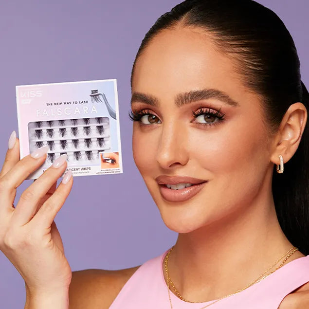 A woman is holding up a box of Falscara eyelash wisps. This package includes 24 eyelash wisps for a DIY lash extensions look.