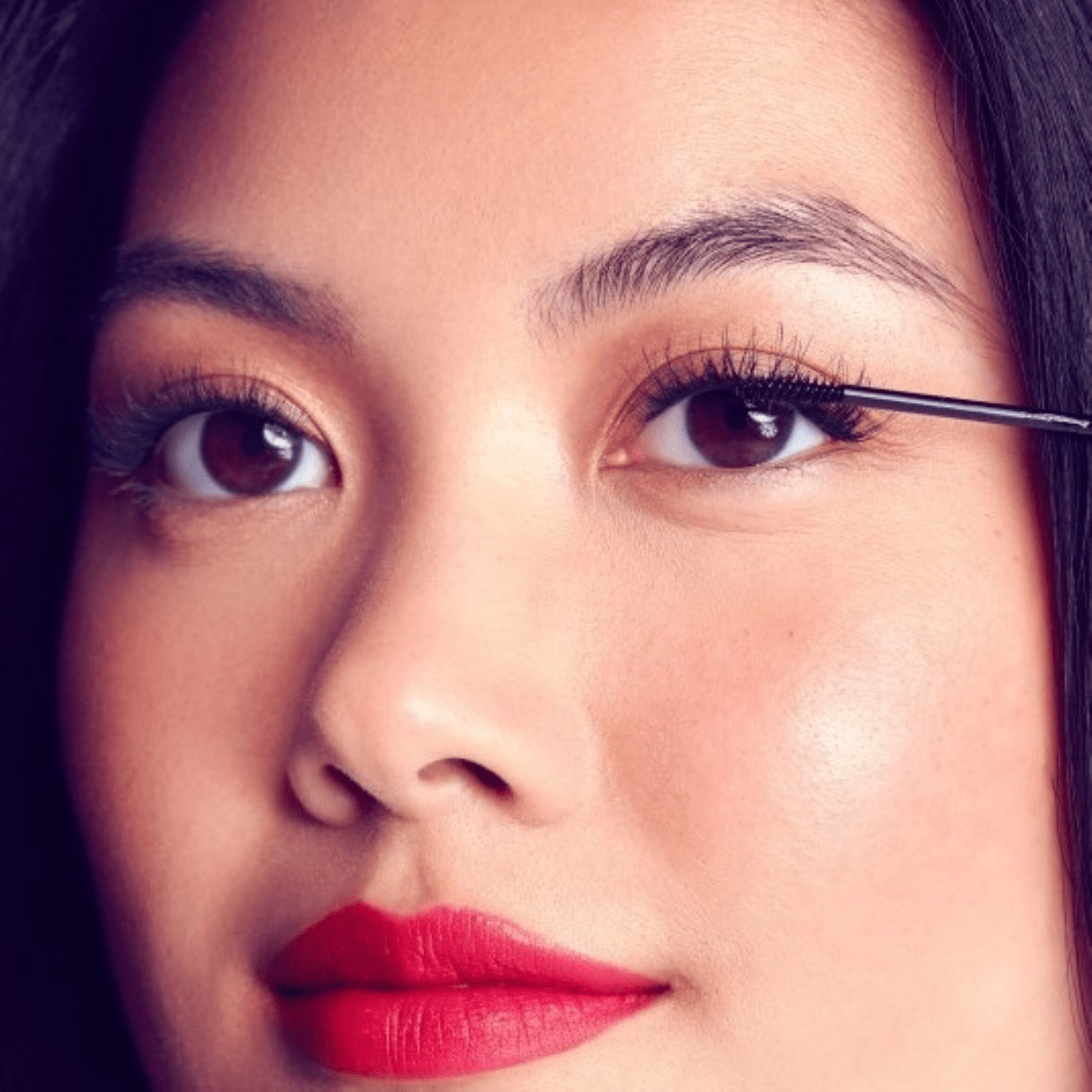 Close-up of a person applying eyeliner with a brush.