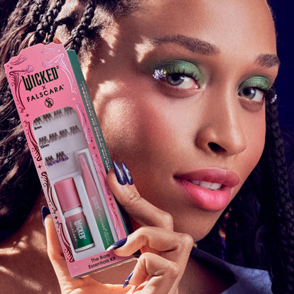 Woman holding Wicked palette with green eyeshadow makeup look displayed.