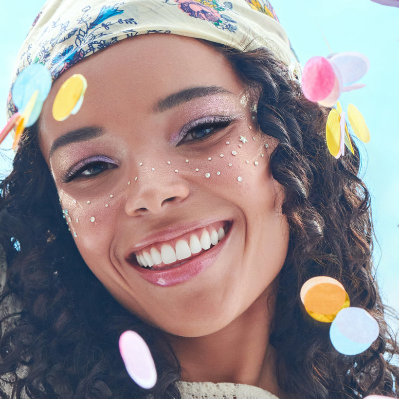 Woman with colorful polka dot headband and face paint against a blue sky