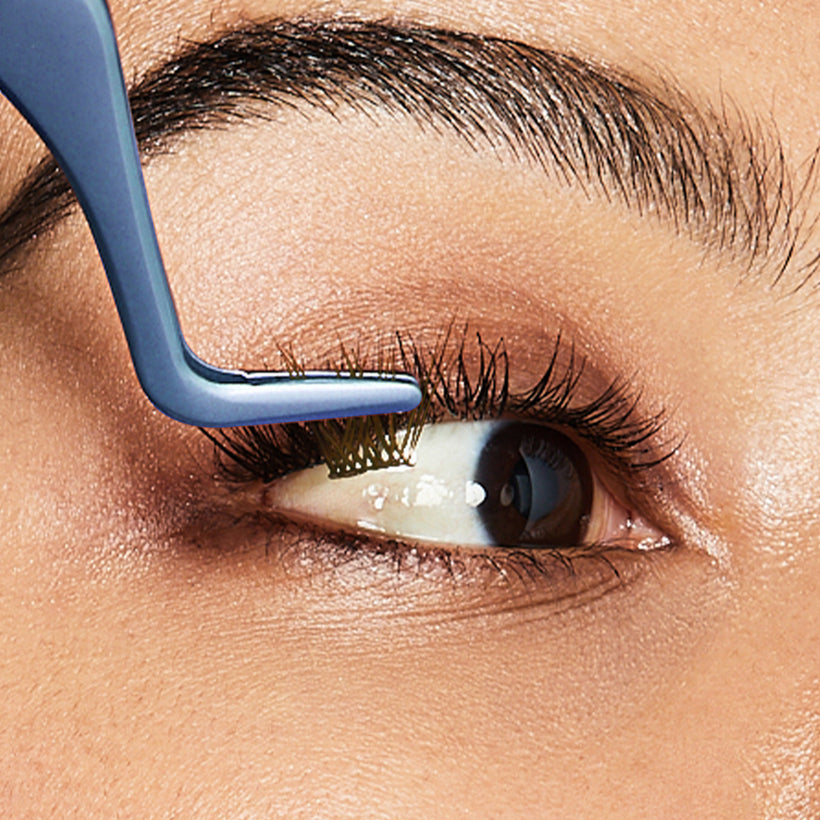 Close-up of eyeliner application with blue brush tool on upper lash line.