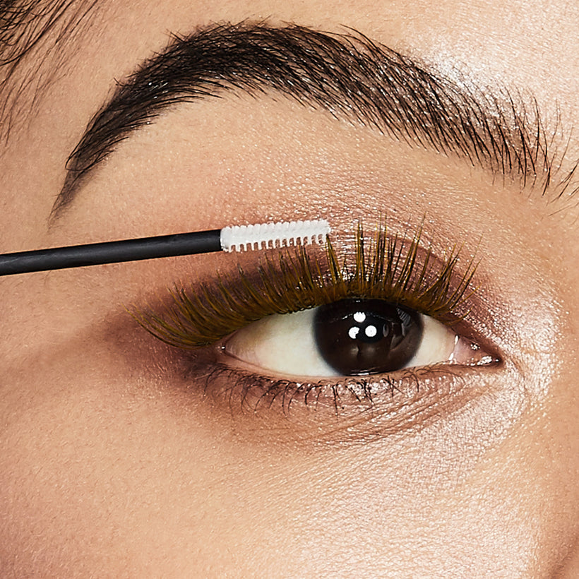 Eyebrow brush applying product to clean eyebrow during makeup application tutorial.