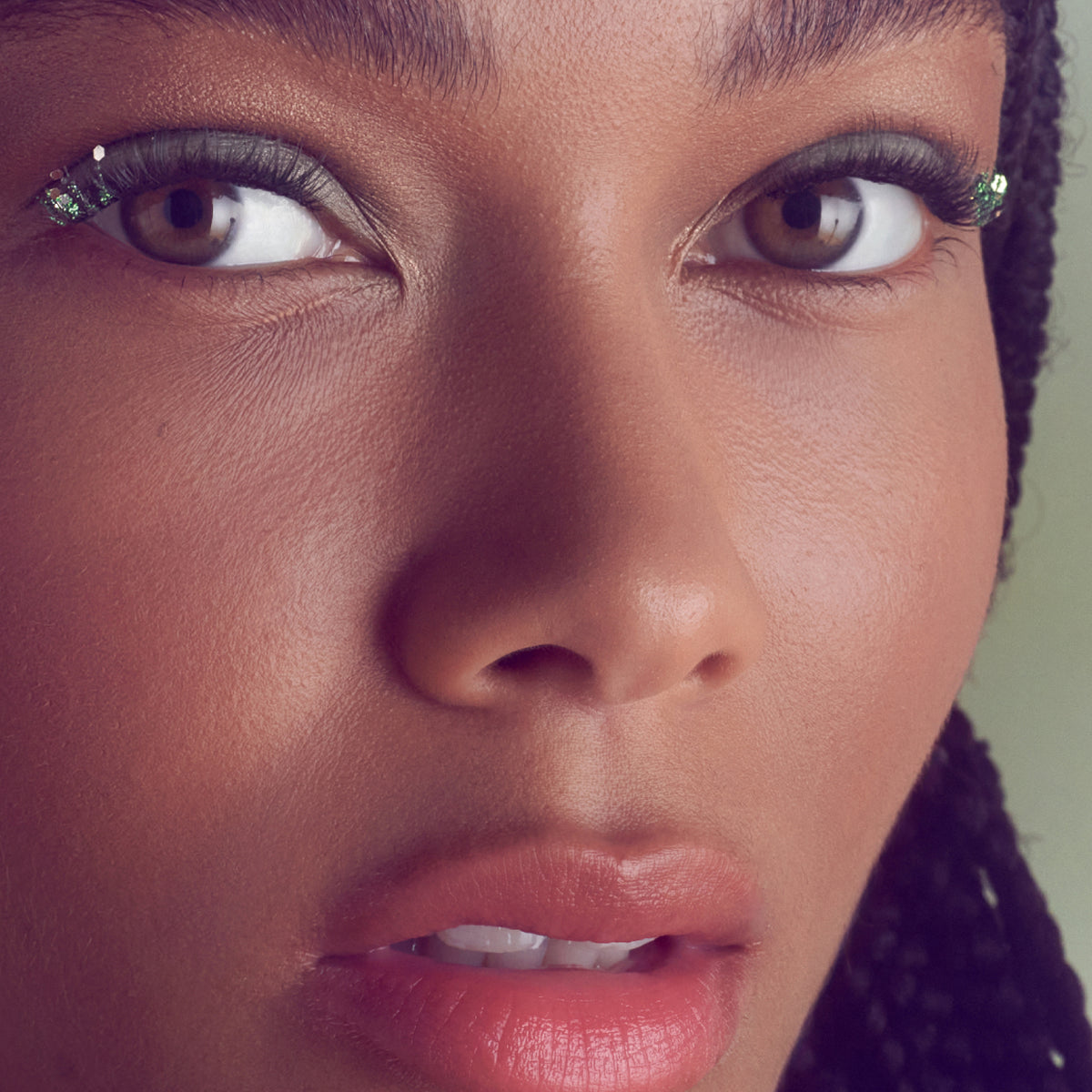 Close-up of woman's face with bold eyeliner, glittery eyeshadow, and nude lipstick.