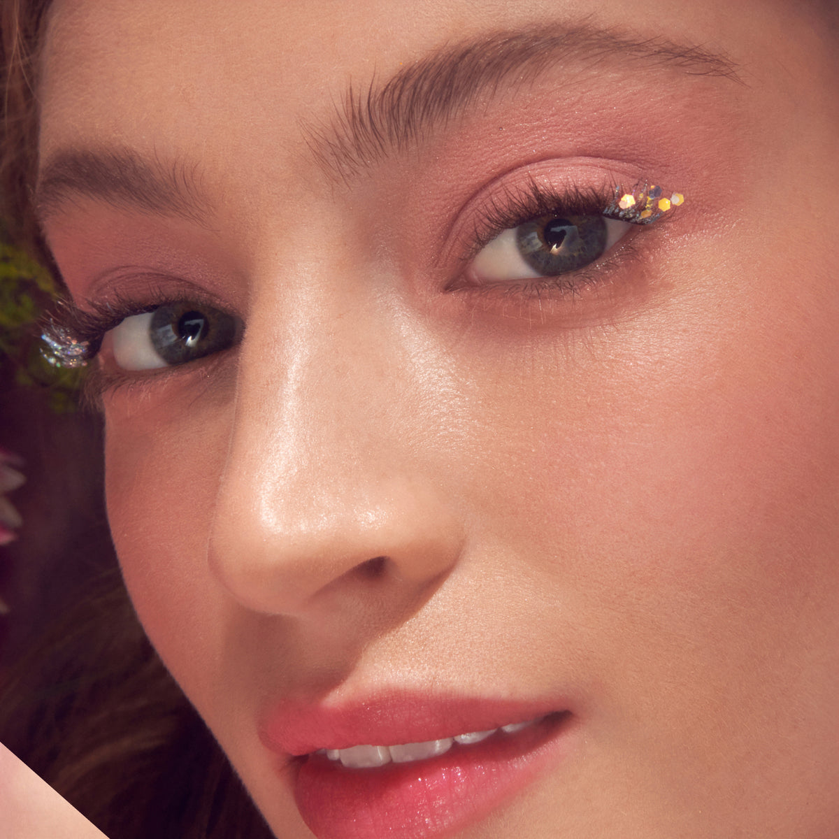Close-up of eye makeup featuring gold glitter eyeshadow and false lashes with dewy skin.