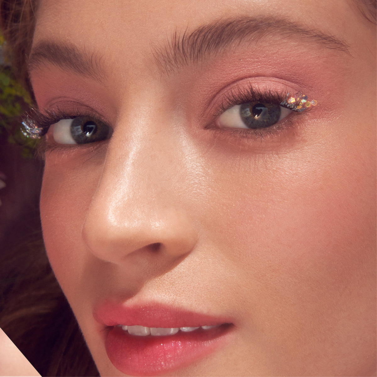 Close-up of eye makeup featuring false lashes and gold glitter eyeshadow.