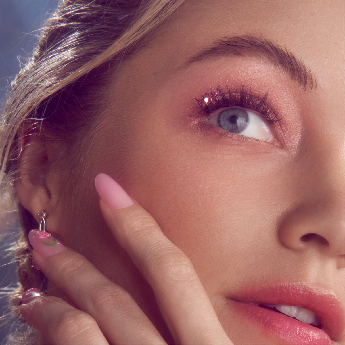Close-up of eye makeup featuring burgundy eyeshadow and false lashes with manicured nails.