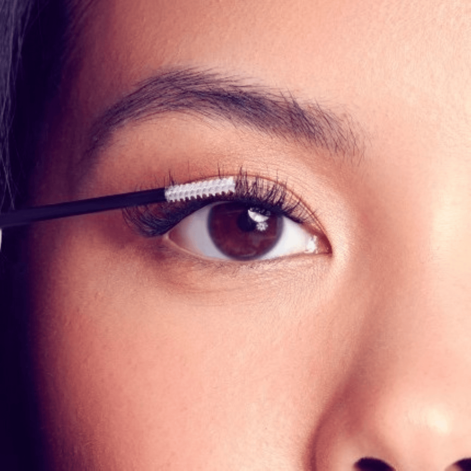 Close-up of a person applying mascara to their eyelashes.